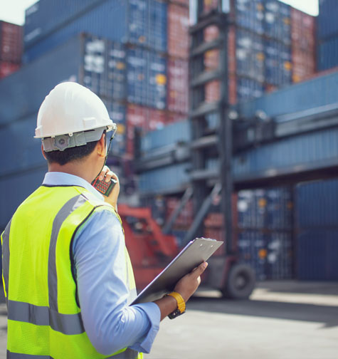 Industriehafen-Logistik - Eine Person arbeitet auf einem Industriehafen, um Fracht zu verladen und zu transportieren, während im Hintergrund digitale Anwendungen und Technologie für eine optimierte Logistik sorgen.
