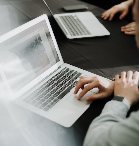 Teamarbeit in der Unternehmensberatung: Zwei Berater arbeiten an einem Tisch mit Laptops, um Geschäftslösungen für Kunden zu bieten.